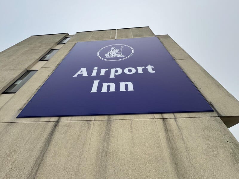 An image of the blue Airport Inn signage on the top of the building.